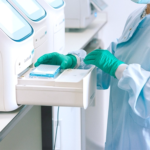 A scientist inserts a sample into a PCR machine.