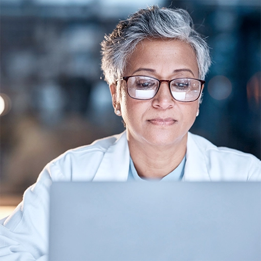 An oncologist reviews test results on a laptop.